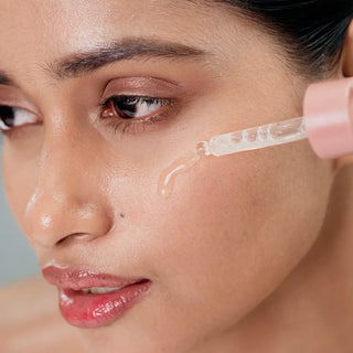 Woman applying a age arrest serum skincare product to her face with a dropper.